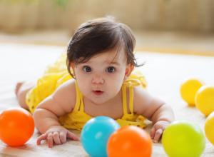 Infant girl crawling after balls