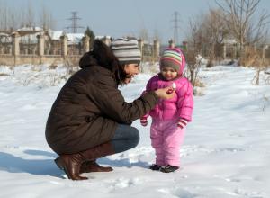 Child playing in snow with caregiver.