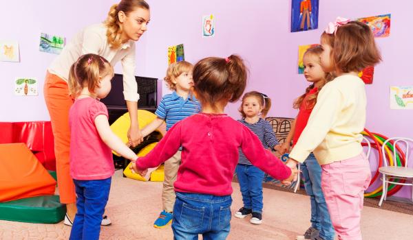 Children with early years provider playing in a circle