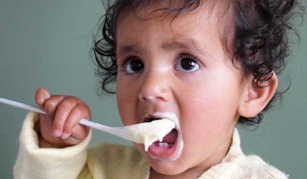Baby eating food with a spoon.