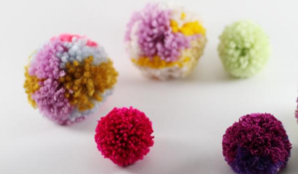 Colourful pom poms  on white surface