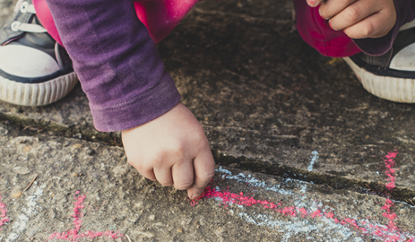 Child writing on sidewalk with chalk