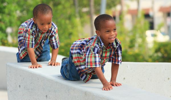 Two boys crawling along a ledge