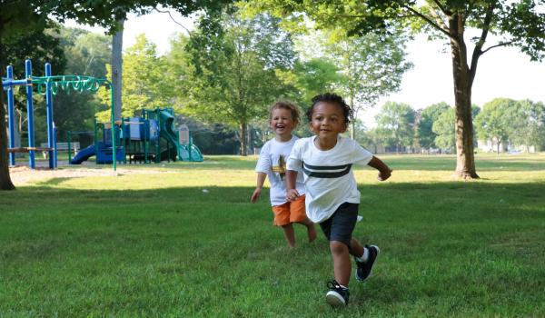 Two children running outside on grass.