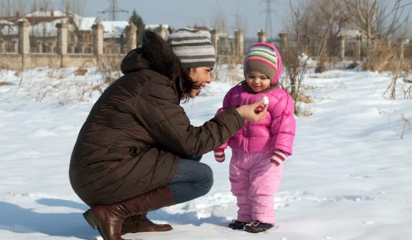 Child playing in snow with caregiver.