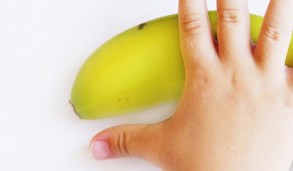 Child's hand reaching for a banana