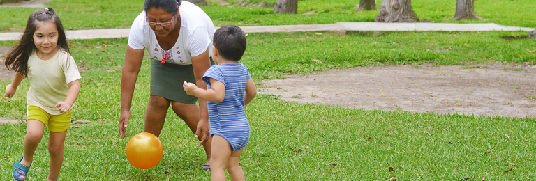 parent playing with two small kids outside