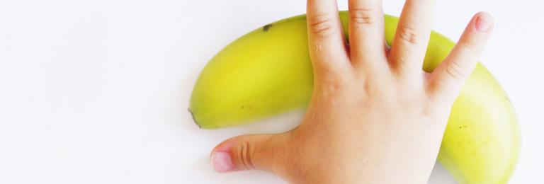 Child's hand reaching for a banana