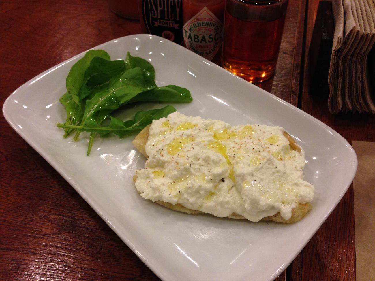 Ricotta cheese on a cracker with spinach.