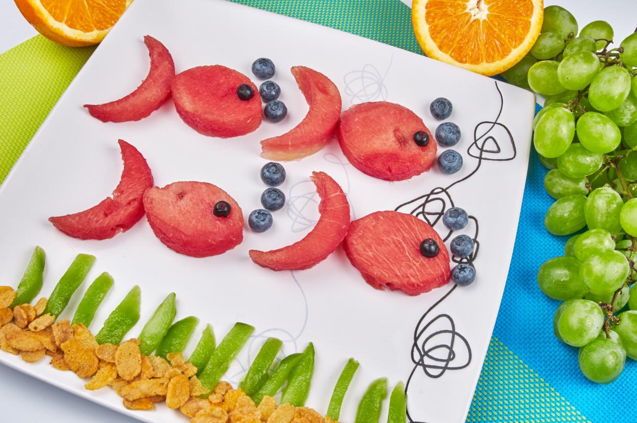 Fish made out of fruit on a white plate.